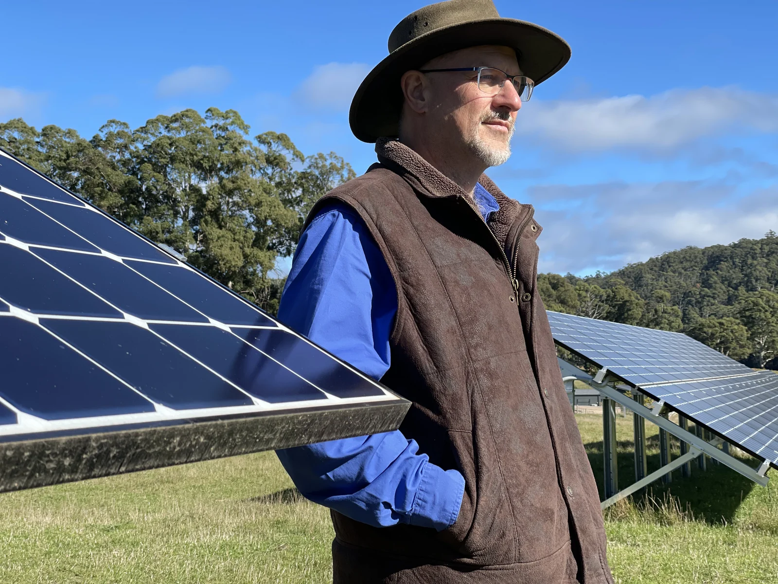 Simon Hackett standing among ground-mounted solar arrays on a sunny day